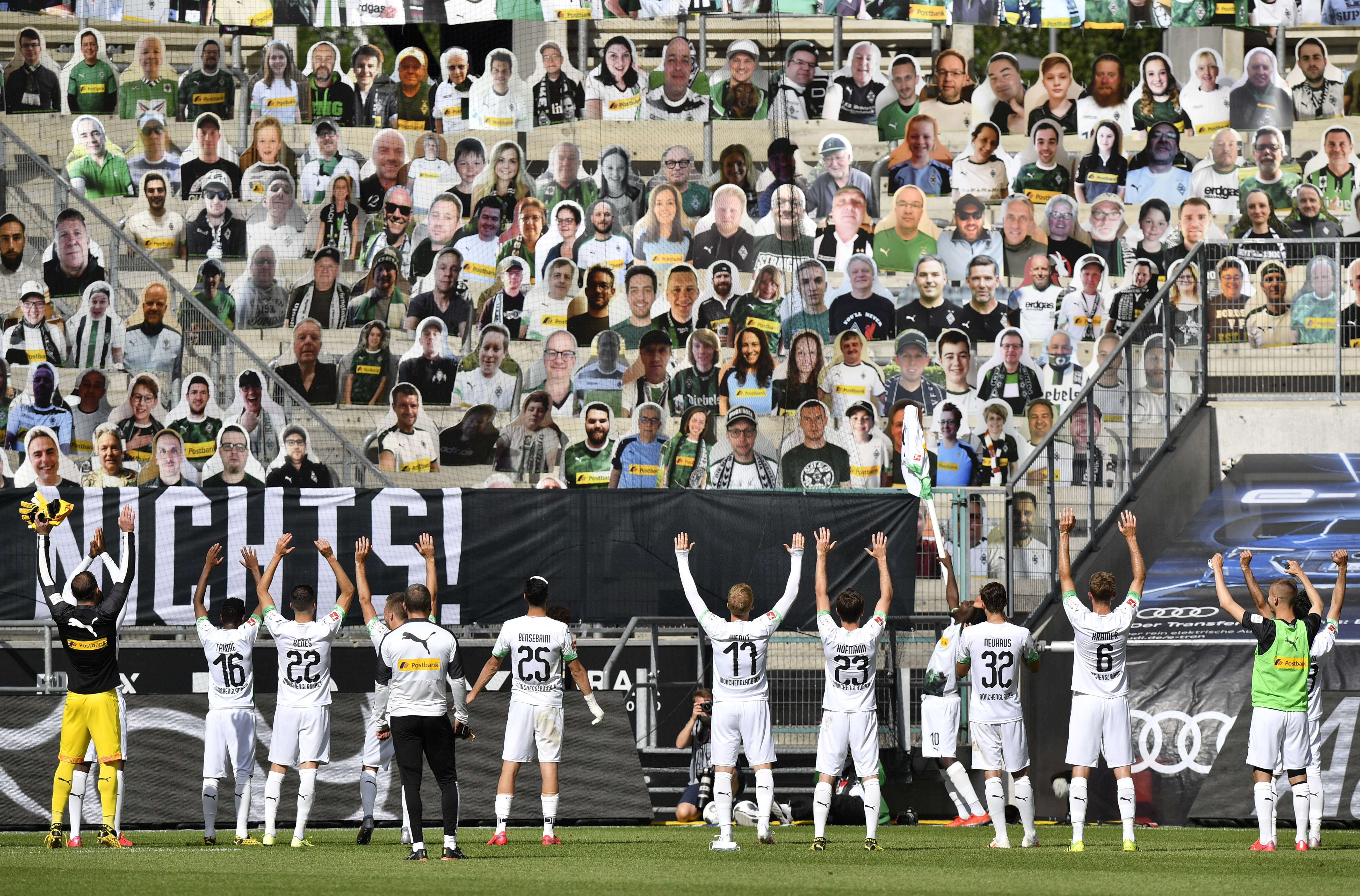Una imagen por demás surrealista. Los jugadores del Borussia Moenchengladbach saludan a los “espectadores en modo cartulina” en las tribunas. (Foto/AP)