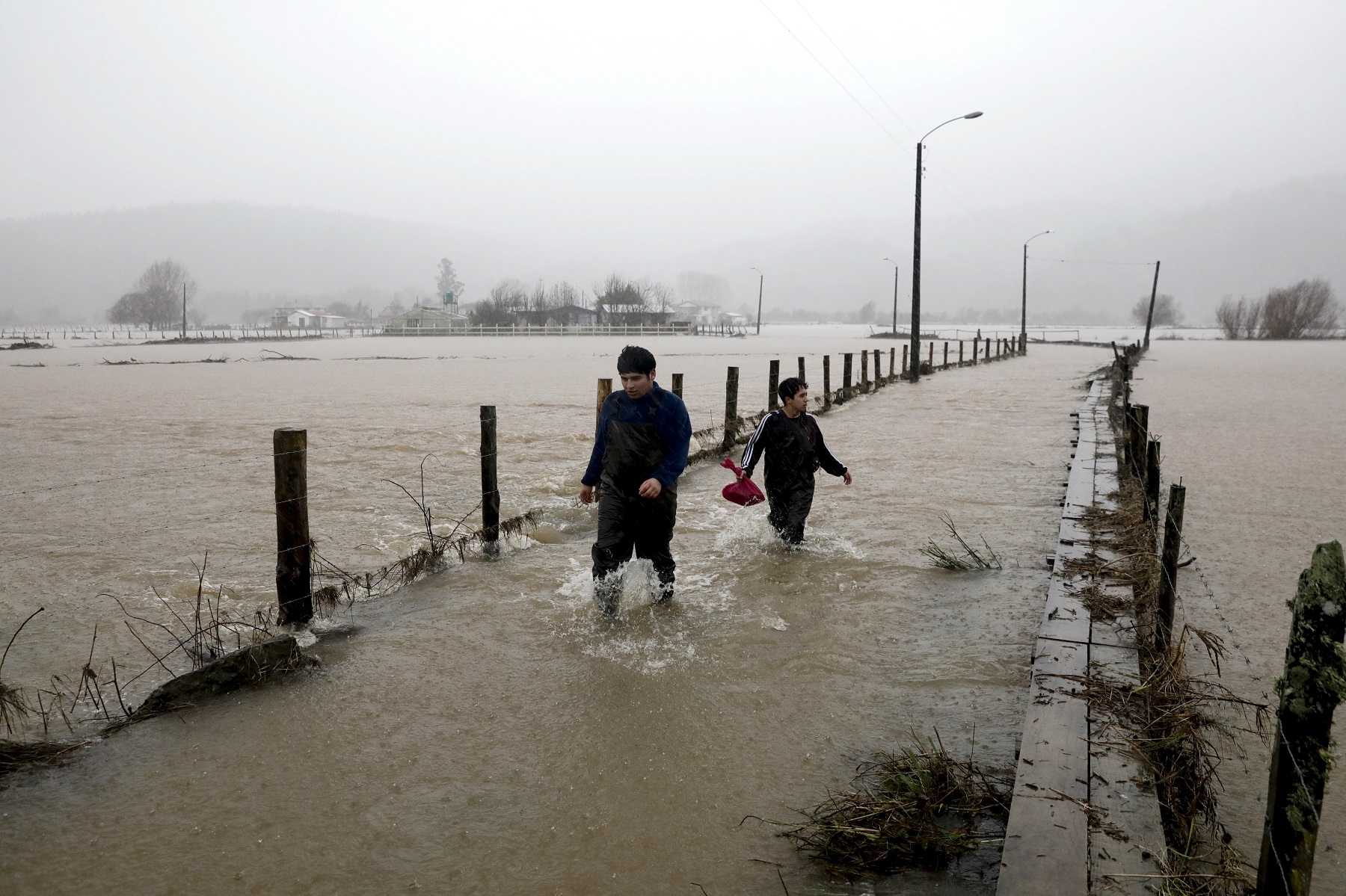 vecinos caminan por una ruta inundada por las tormentas. Foto AP