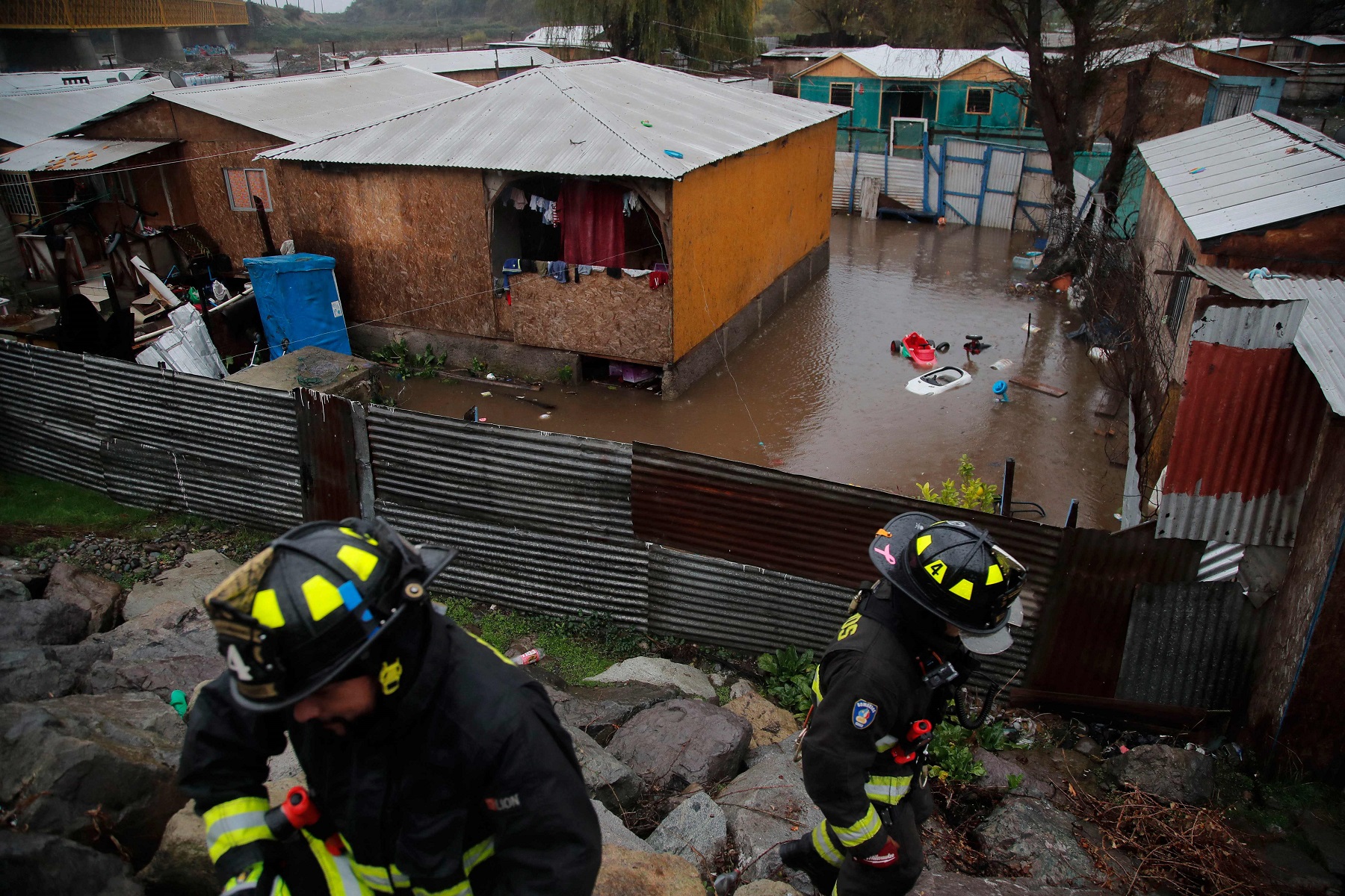 Bomberos evacuan a residentes de una barriada ubicada a orillas del río Mapocho. Foto AFP