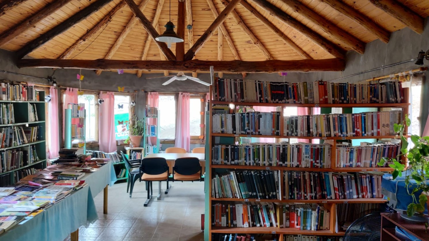 Estanterías y el paisaje del otro lado de las ventanas de la Biblioteca, desde donde se observa el cerro "La Corona". Foto: Gentileza.