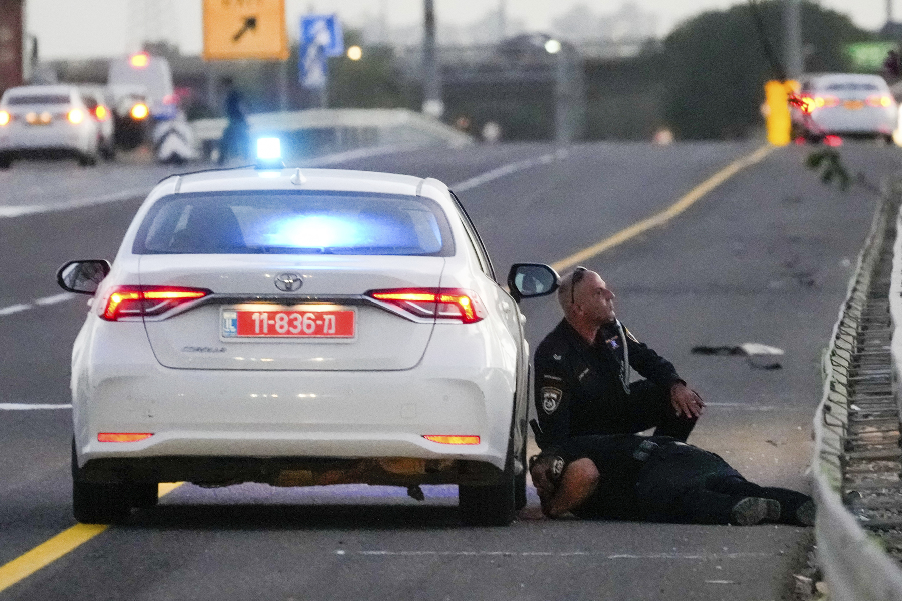 Policías se protegen de los misiles lanzados desde Irán que impactaron en Israel. (Foto AP/Ohad Zwigenberg)