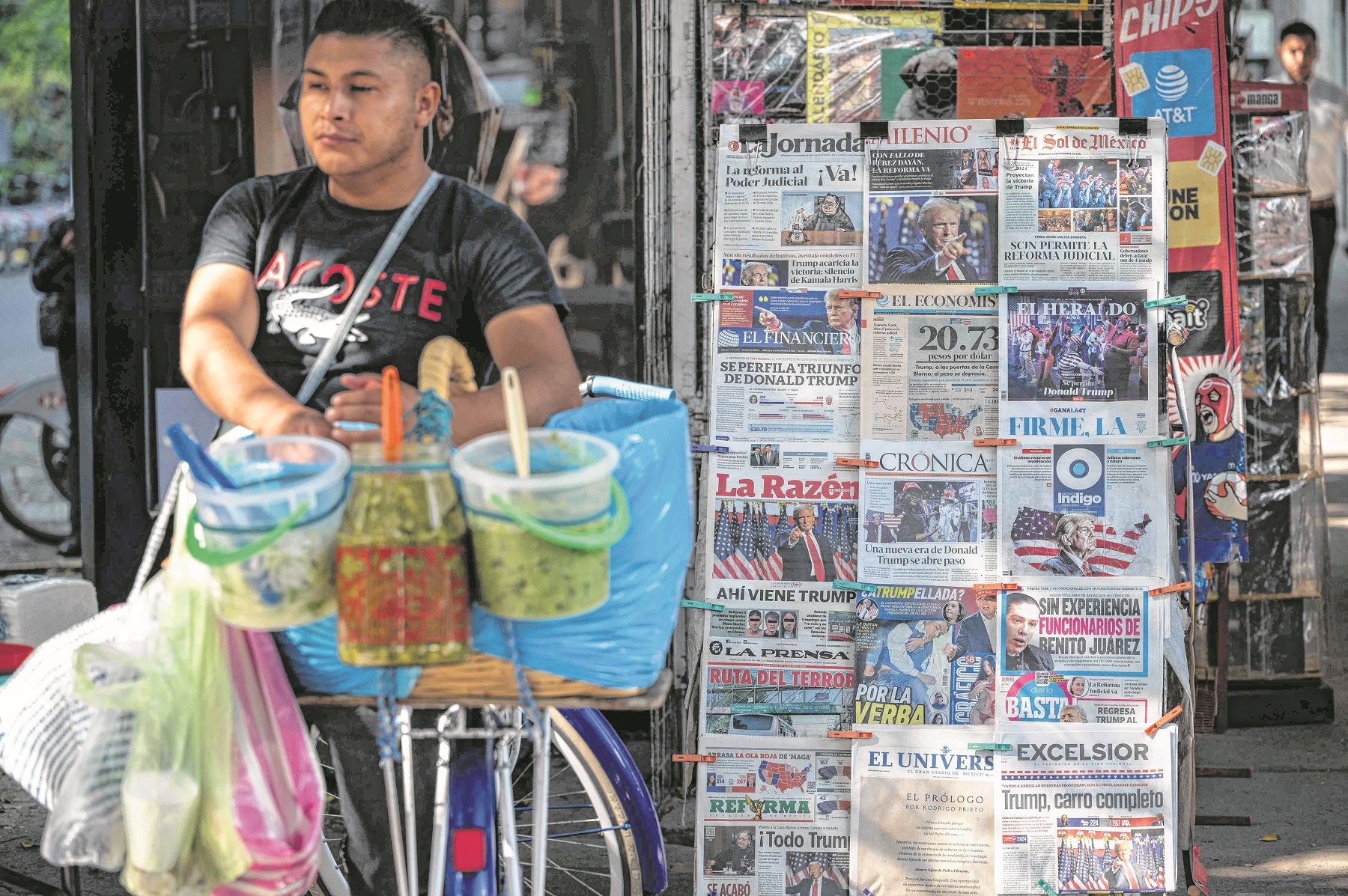  Un hombre vende tacos en un puesto con diarios que informan la victoria de Trump (Photo by Yuri CORTEZ / AFP)